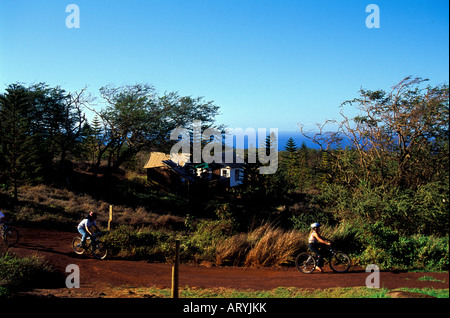 Bicyclists riding in Paniolo Camp with the Tentalow's in the background on Molokai Ranch Stock Photo