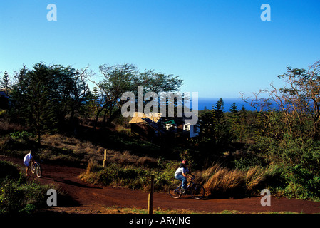 Bicyclists riding in Paniolo Camp with the Tentalow's in the background on Molokai Ranch Stock Photo