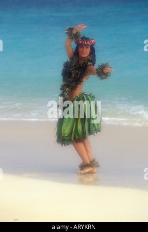 Woman dances hula at Kailua Beach in  ti leaf skirt and leis. Oahu Stock Photo