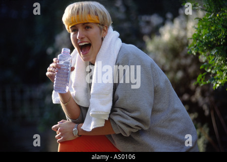 Young blond woman drinking mineral water after an aerobics workout. Stock Photo