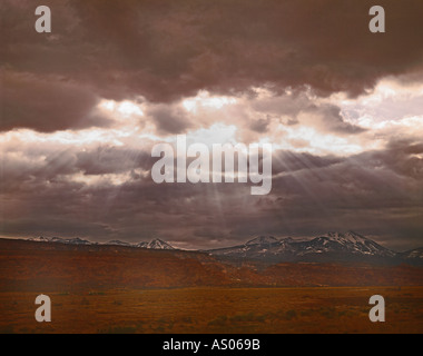 Dramatic Utah sky with sun bursting through the clouds and creating rays of light darting toward the earth Stock Photo