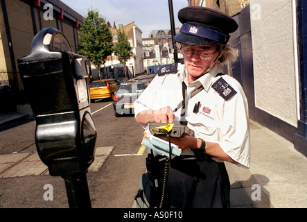 Traffic warden placing parking ticket on windscreen of car. Stock Photo