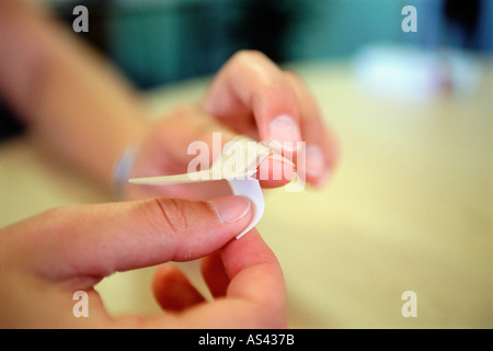 A person putting a plaster on their finger Stock Photo