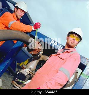 Construction workers adjusting pipe Stock Photo