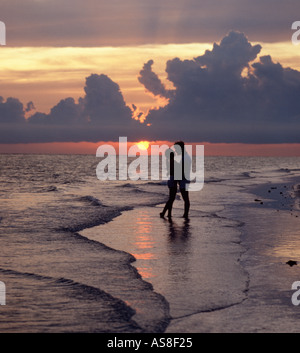 couple embrace on beach at sunset Stock Photo
