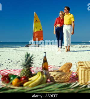 young couple enjoying a picnic at the beach after a sailboat ride Stock Photo