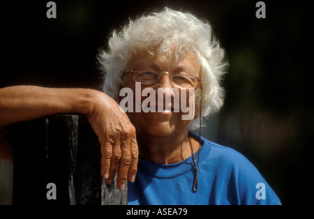 Older senior woman with white hair and glasses smiles and looks happy Stock Photo