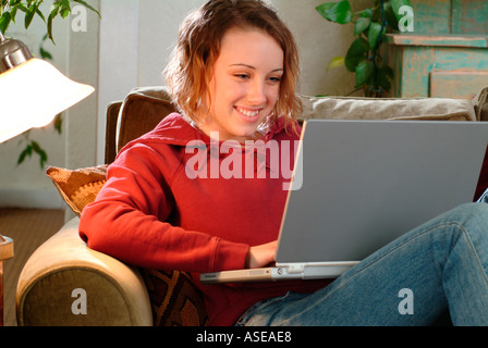 18 year old woman working on a laptop on the couch Stock Photo