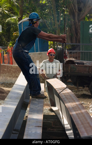 Two laborers in hard hats moving steel beams into position at a building site. Stock Photo