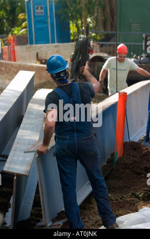 Two workers in hard hats moving steel beams into position at a building site. Stock Photo