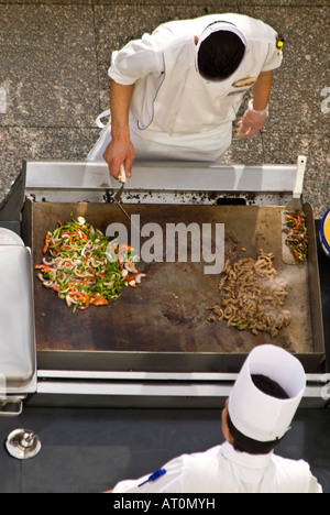 Vertical aerial close up of two chefs in whites preparing a stir fry outside on a hotplate Stock Photo