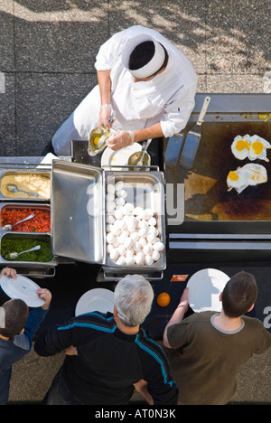 Vertical close up of a chef in whites frying eggs and omelettes to order for peoples breakfasts Stock Photo