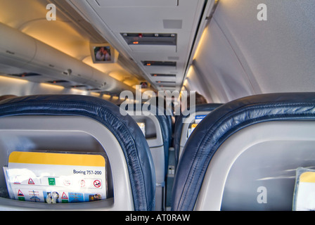 Horizontal wide angle of passengers sitting inside an aeroplane watching the inflight entertainment