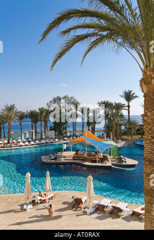 Vertical view of a hotel swimming pool with a swim up bar surrounded by palm trees on a bright sunny day Stock Photo