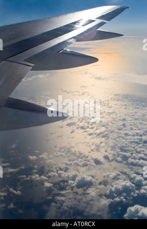 Vertical wide angle of the sun setting and clouds reflected on the sea from inside an aeroplane Stock Photo