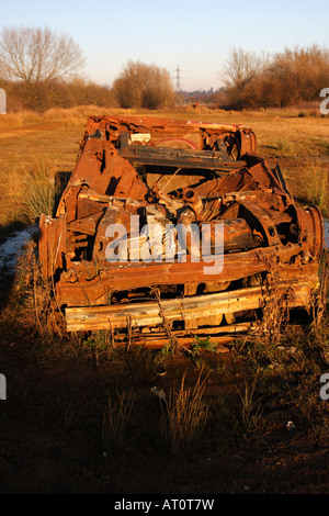 'Burnt out' abandoned car 'upside down' in field, England, UK Stock Photo