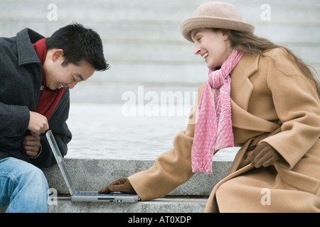 Young woman using a laptop with her friend Stock Photo