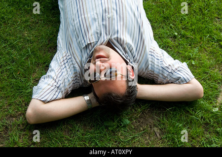 Man laying on the grass relaxing in the park Stock Photo