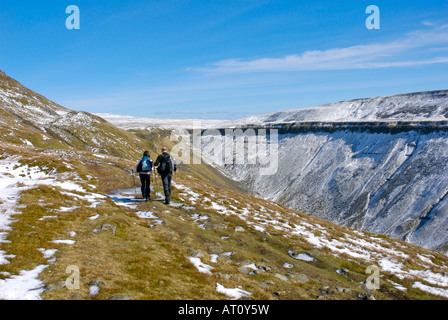 Two walkers approaching High Cup Nick in the snow, North Pennines, Cumbria, UK Stock Photo