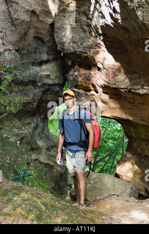 Young Man with Backpack Standing in front of Small Stone Arch Red River Gorge Geological Area Kentucky Stock Photo