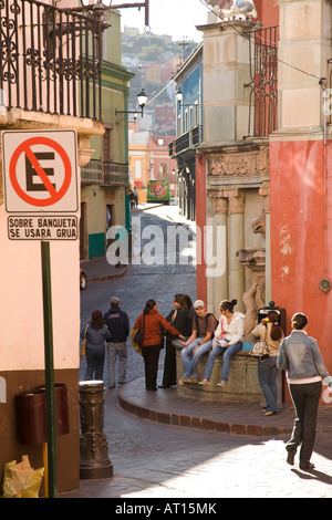 MEXICO Guanajuato University students standing and sitting waiting at bus stop and walking sidewalk no parking sign in Spanish Stock Photo