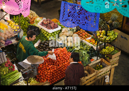 MEXICO Guanajuato Adult male handing food to customer fruit and vegetable vendor in Mercado Hidalgo indoor market Stock Photo