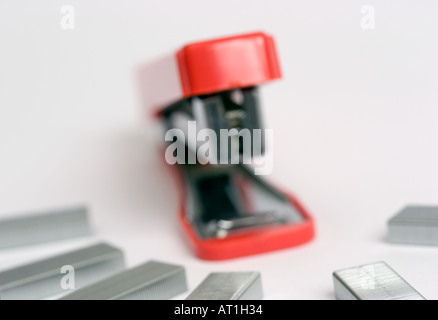 Red stapler surrounded by rows of staples Stock Photo
