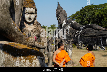 Two novices in front of the reclining Buddha at Xieng Khuan (Buddha Park) near Vientiane, Laos Stock Photo