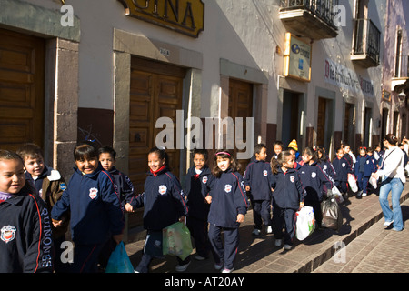 MEXICO Guanajuato Large group of young students in school uniforms walking down sidewalk holding hands Stock Photo