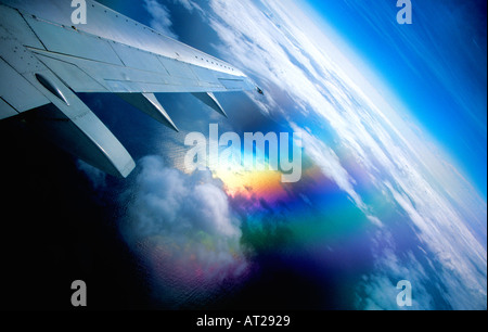 Airplane window view with clouds and polarised polarized reflection of sun shining on wing and sea Stock Photo