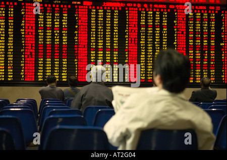 People looking at the stock market prices on a display board Stock Photo