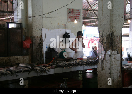 Trader having a cigarette while selling fresh fish in the wet market off the Main Bazaar in Kuching, Sarawak, Borneo, Malaysia Stock Photo