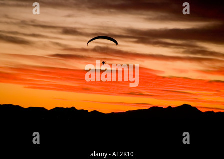A parasailer is silhouetted against a sunset over the Sierrita Mountains in Tucson Arizona USA Stock Photo
