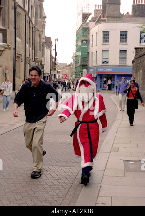 A young man in a Santa Claus suit heads for Christmas work at a local store in the university town of Cambridge England Stock Photo