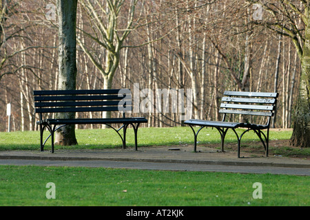 two empty park benches in winter sunlight in park Stock Photo