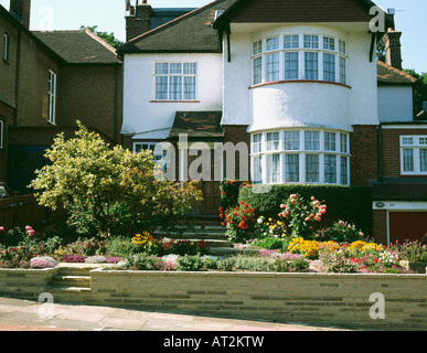 Thirties detached house with bay window and colorful plants in small front garden Stock Photo