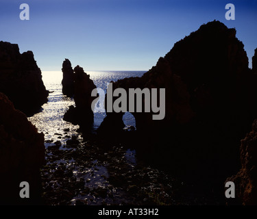 Eroded sandstone sea cliffs and arches at Ponta da Piedade, Algarve, Portugal silhouetted against the sun Stock Photo