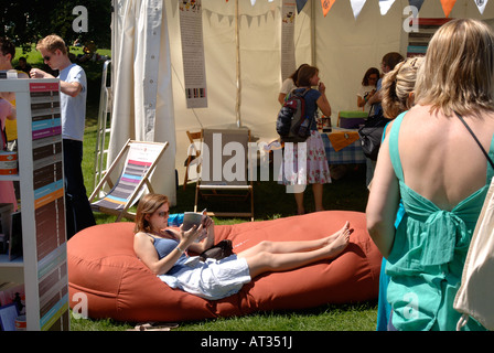 A GIRL READING OUTSIDE THE BOOKSHOP AT THE INNOCENT VILLAGE FETE IN REGENTS PARK LONDON 2007 Stock Photo