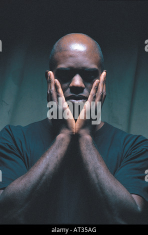 A portrait of a black man, hands on face Stock Photo