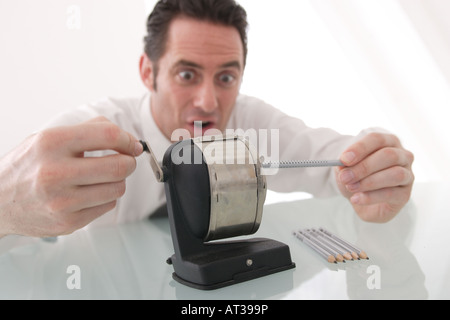 A man sitting at his desk sharpening pencils Stock Photo