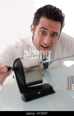 A man sitting at his desk sharpening pencils Stock Photo