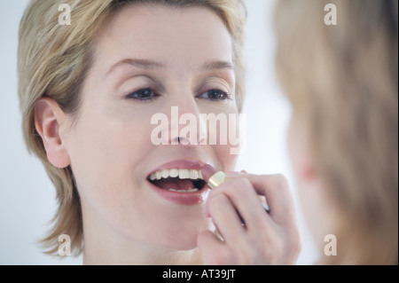A woman applying lipstick in the mirror Stock Photo