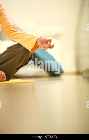 A woman sitting on a yoga mat, close-up of hand Stock Photo