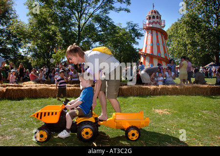 A YOUNG FATHER HELPS HIS CHILD PLAY ON A TOY DUMP TRUCK AT THE INNOCENT VILLAGE FETE IN REGENTS PARK LONDON 2007 Stock Photo
