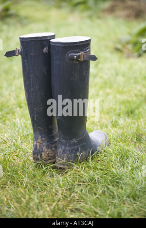 Muddy Wellington boots standing in the grass Stock Photo