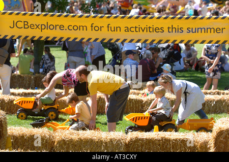 A FATHER HELPS HIS CHILD PLAY ON A TOY DUMP TRUCK AT THE INNOCENT VILLAGE FETE IN REGENTS PARK LONDON 2007 Stock Photo
