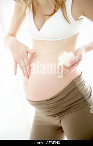 A pregnant woman applying moisturising cream to her tummy