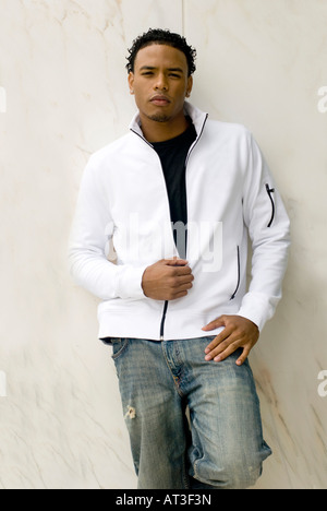 Attractive young man in a stylish jacket and jeans on against the wall Stock Photo