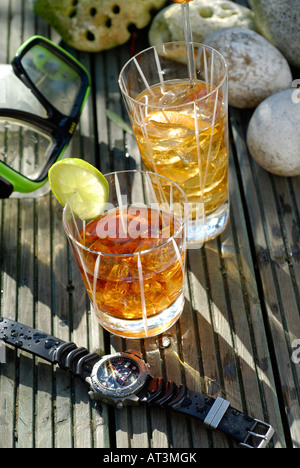 Two glasses of rum on sunlit wet decking Stock Photo