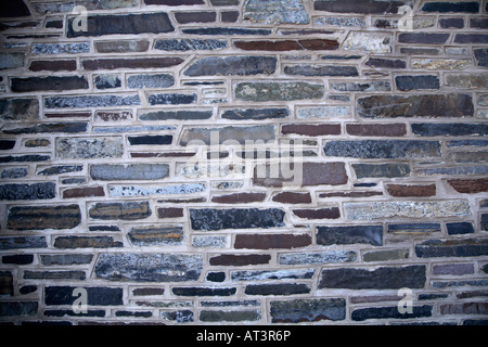 Varied stone wall.  Flat oblong stones in varing widths and materials with thick concrete around them. Stock Photo